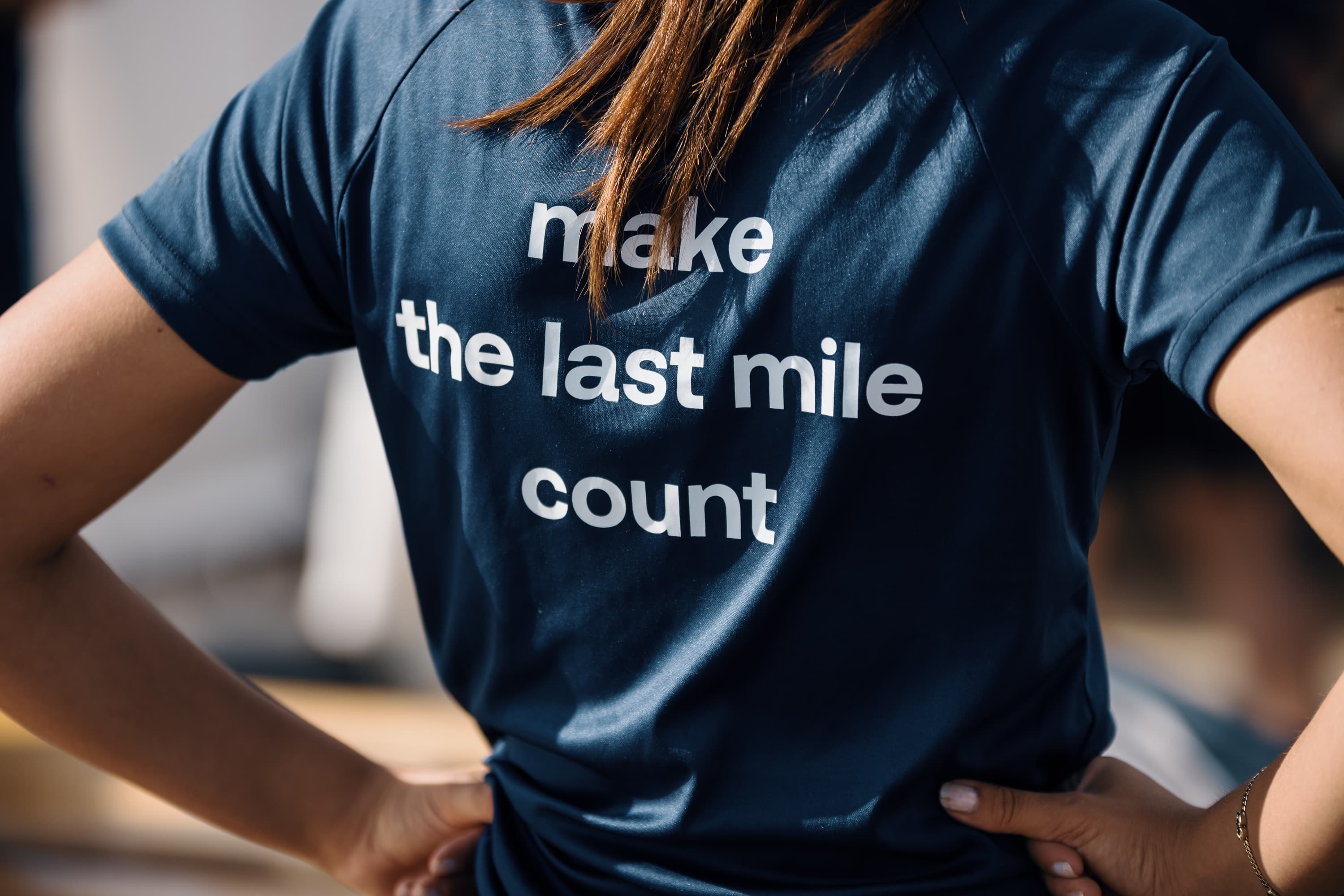 Persoon draagt een blauw shirt met de tekst 'Make the last mile count' op de achterkant.