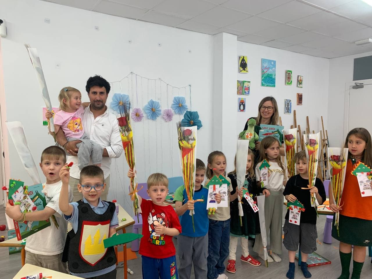 A group of people stand in a classroom, holding colourful cone-shaped gifts and papers, with art and decorations on the walls.