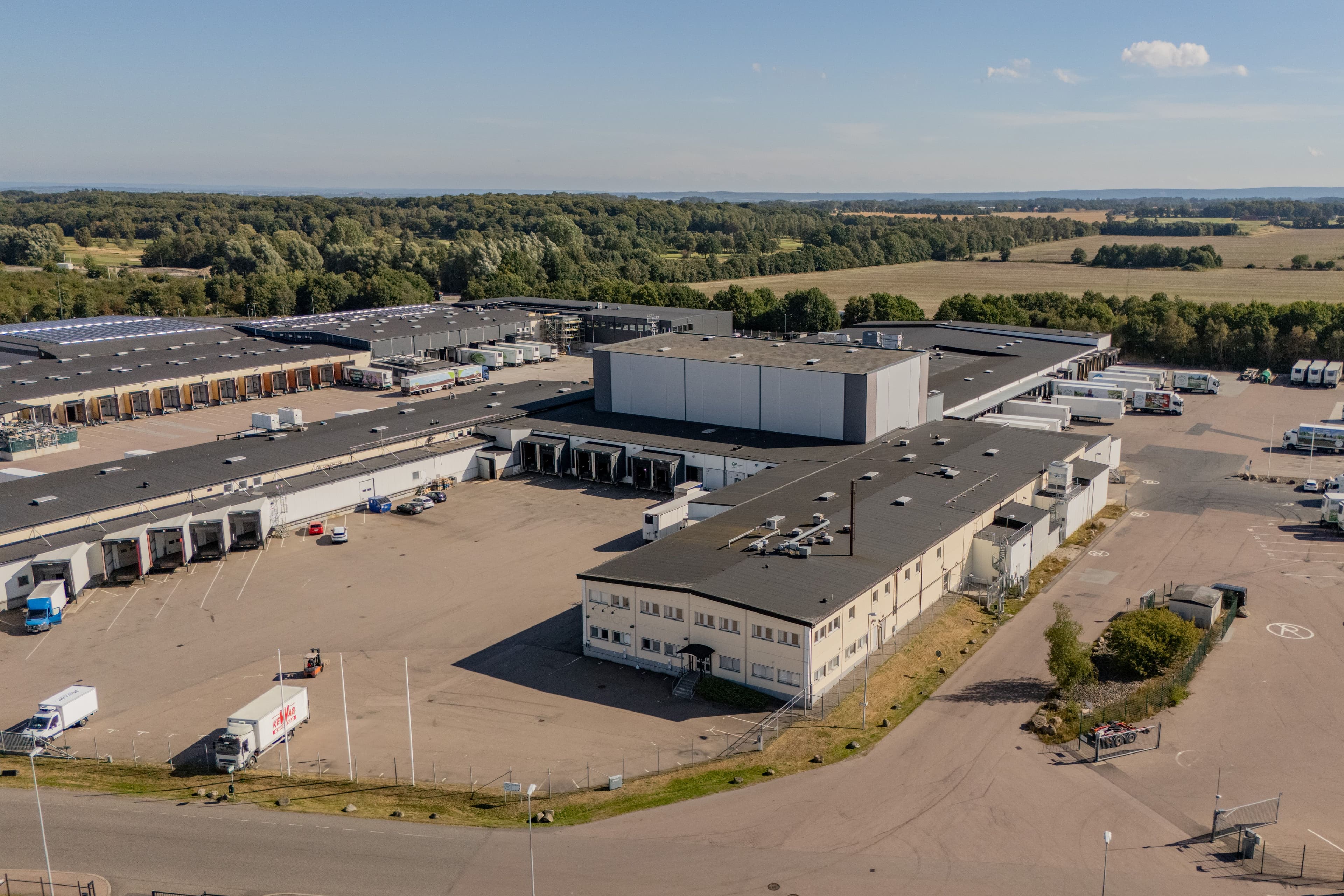 Aerial view of a large warehouse and logistics centre with multiple loading bays and lorries parked in the yard.
